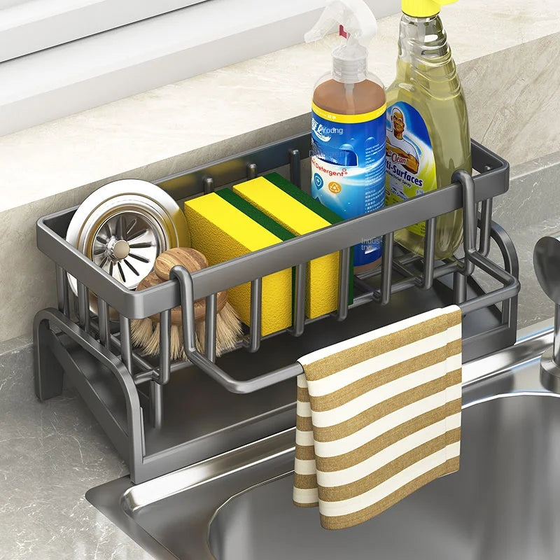 Glow Market Home kitchen sink organizer rack with compartments holding scrub brushes, sponges, soap, and a hanging towel